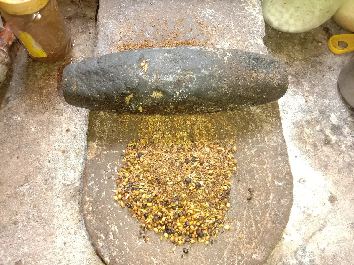 Spices being ground by hand on a shil-pata grinding stone