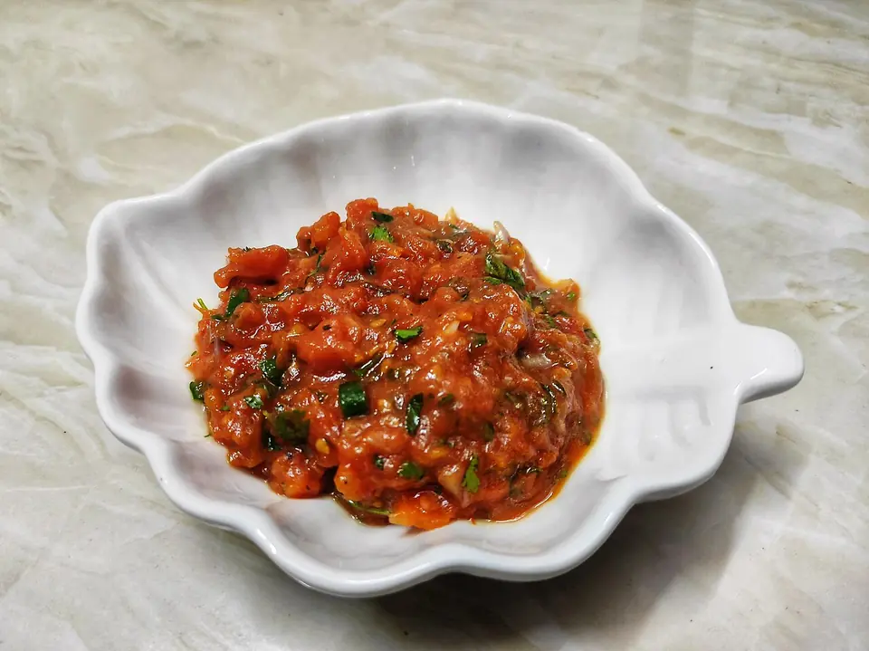 Homemade Bangladeshi tomato vorta with coriander and green chili in a white leaf-shaped dish