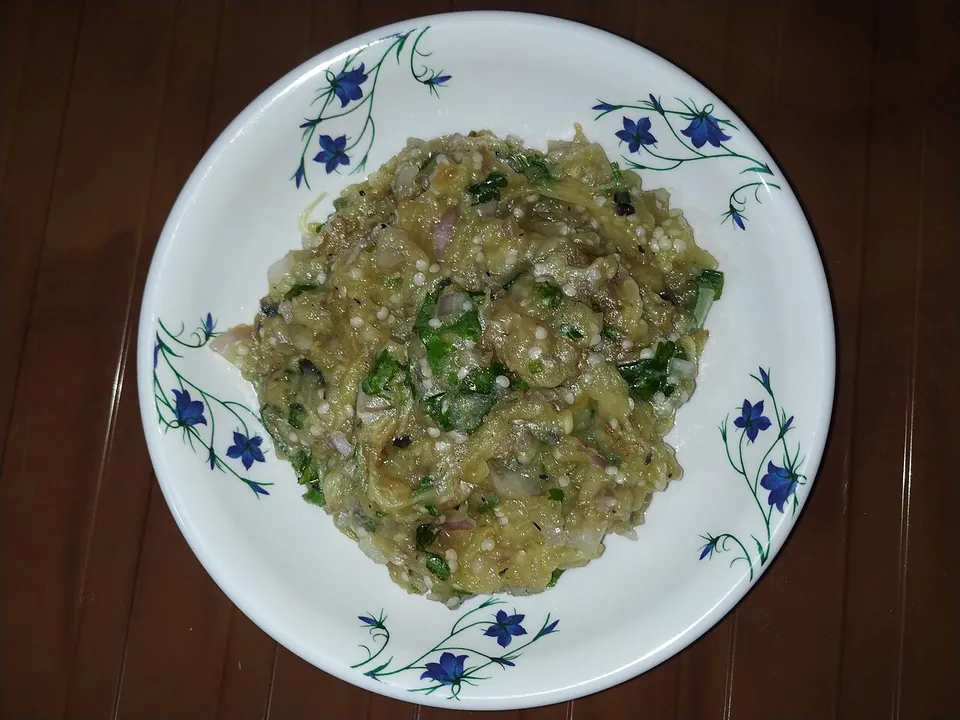 Begun vorta — smoky mashed eggplant with onion and cilantro on a floral plate